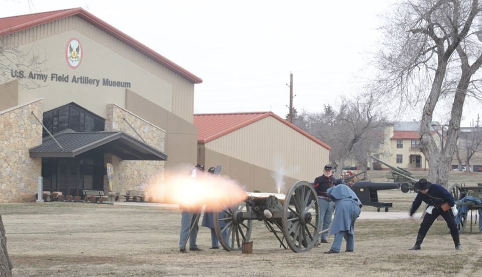 Outside the front entrance of the U.S. Army Artillery Musuem. Several people involved in a combat reenactment and firing a canon.